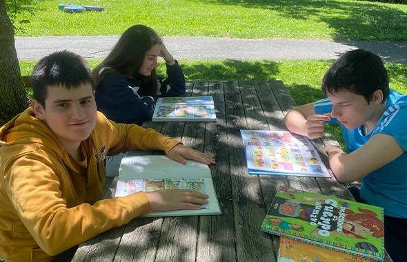 grupo-jovenes-leyendo-mesas-aire-libre